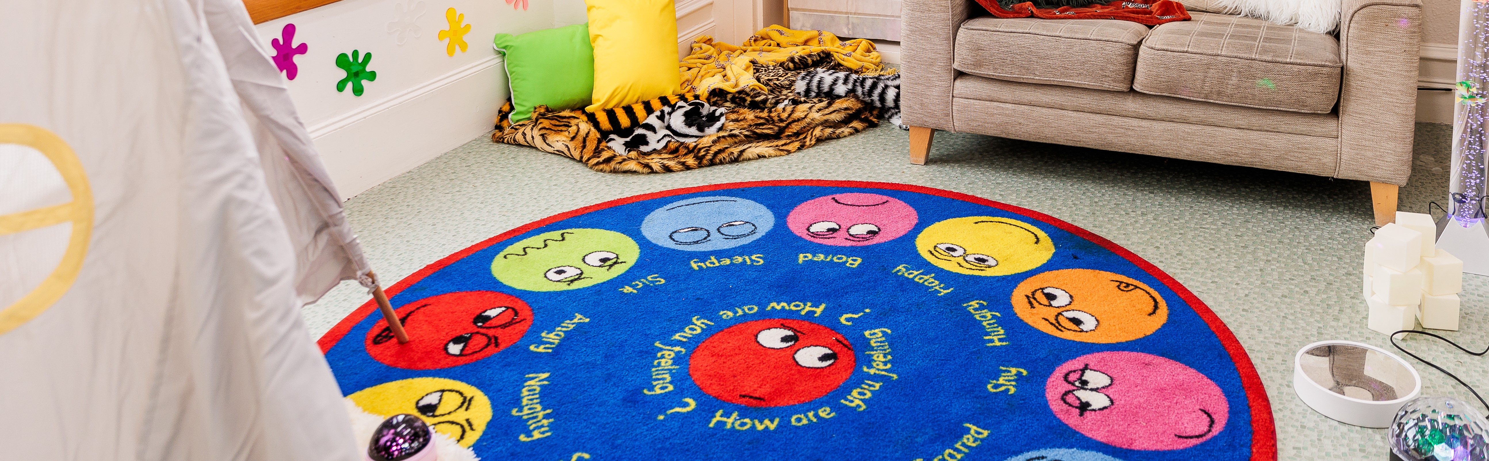 Colourful children's rug with smiling faces, surrounded by playful room decor.