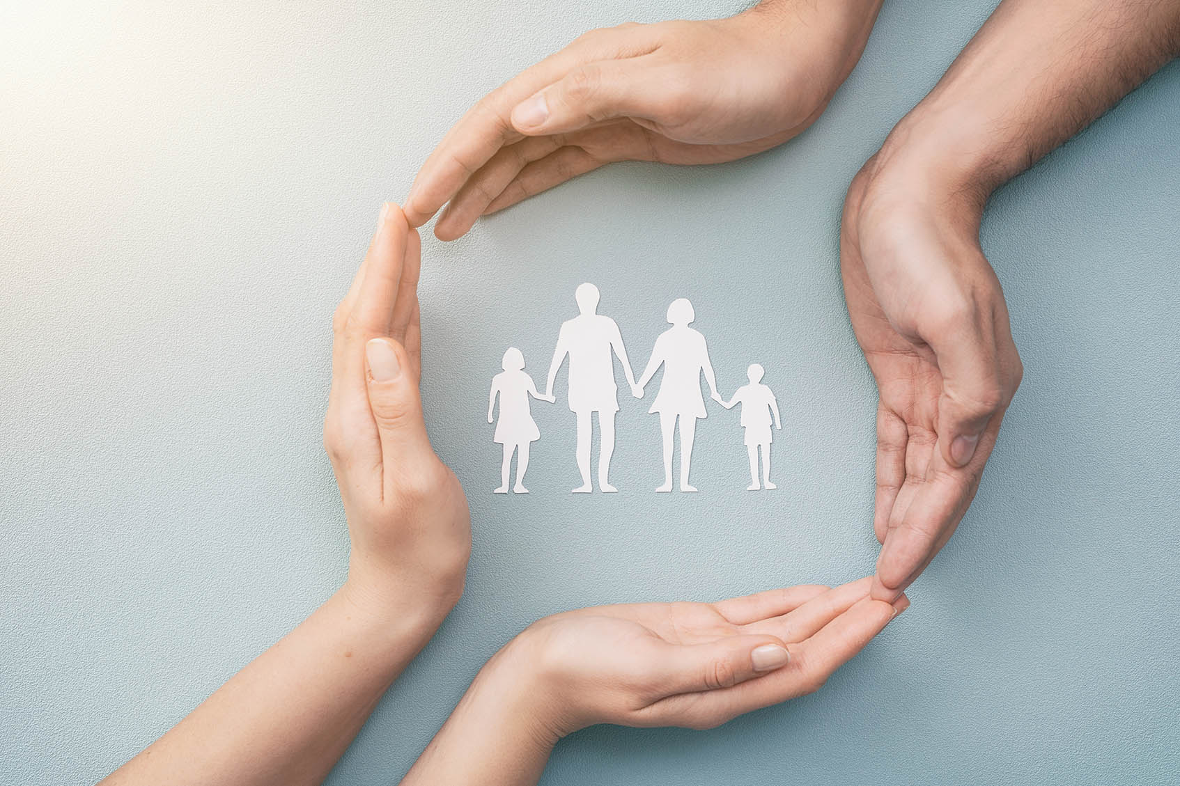 Hands encircling a family icon on a light blue background