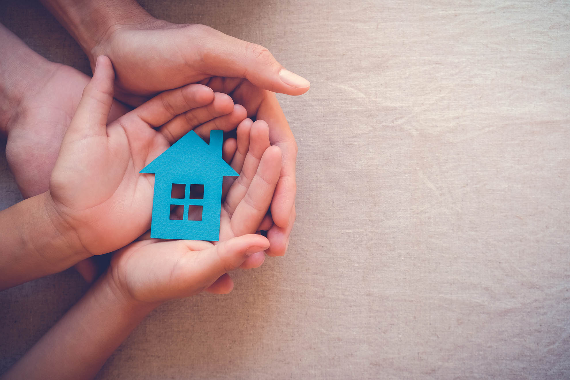 Hands holding a small blue house cutout