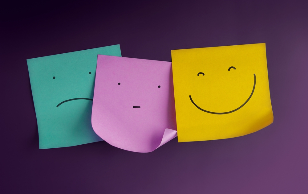 Three sticky notes with sad, neutral, and happy faces on a purple background.